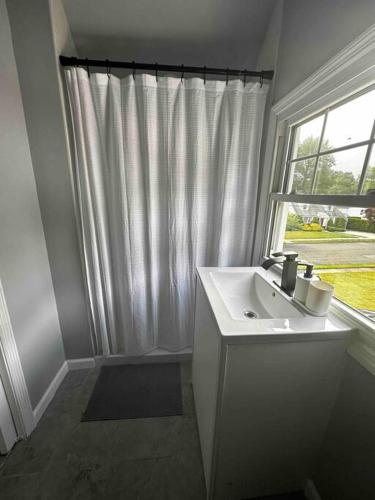 a white bathroom with a sink and a window at Charming Cape Cod Retreat in the Suburbs of NJ in Dumont