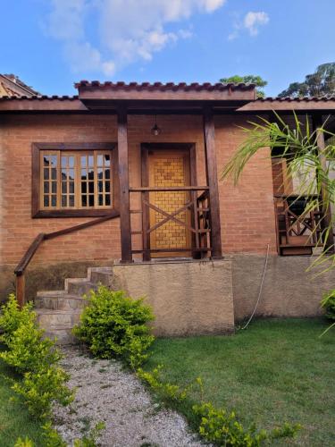 Chalés das cerejeiras في سانتو أنطونيو دو بينهال: منزل من الطوب مع باب أصفر وشرفة