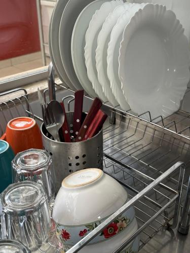 a dish drying rack with plates and utensils in a sink at Casa Lumen in Núcleo Bandeirante