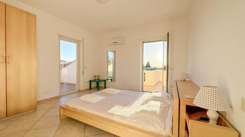 a bedroom with a bed and a desk and windows at Livingapple in Scauri