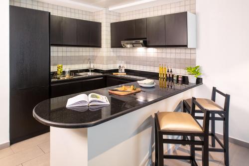 a kitchen with a counter with chairs and a table at Citadines Metro Central Dubai in Dubai