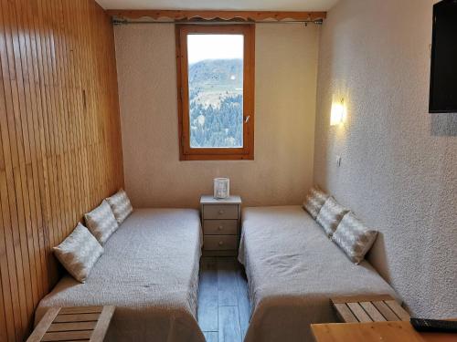 deux lits dans une chambre avec une fenêtre dans l'établissement Appart cosy avec accès pistes et commerces, balcon, parking, animaux ok! - FR-1-355-24, à Les Allues
