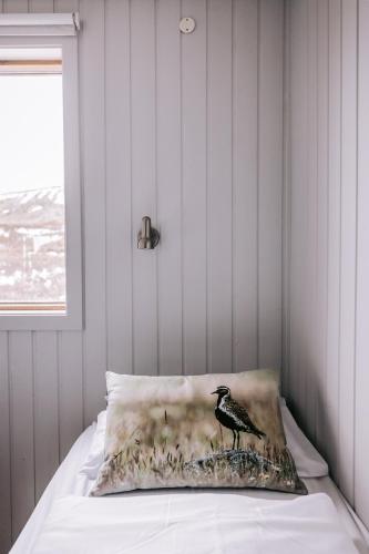 a bird on a pillow on a bed at Hlid Cottages in Myvatn