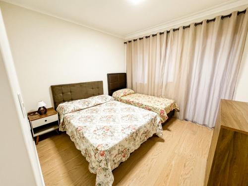 a bedroom with two beds and a window with curtains at Lake's House - Piscina natural aquecida in Socorro