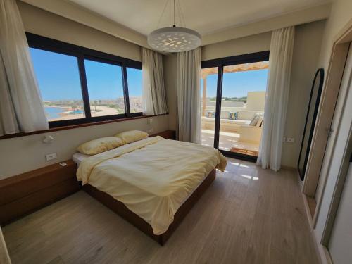 a bedroom with a large bed and large windows at Sunrise to Sunset Rooftop Panorama - El Gouna Shedwan in Hurghada