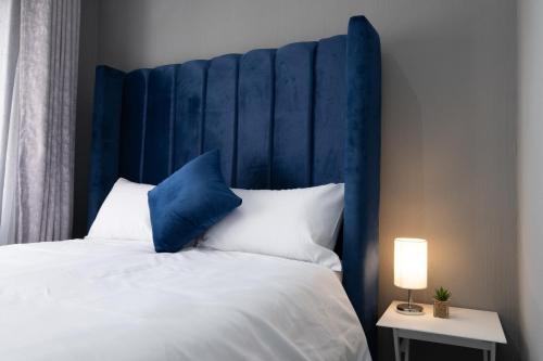 a bed with a blue headboard and white pillows at Explore this stylish and classy apartment in Sandton