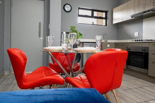 a kitchen with red chairs and a table with wine glasses at Explore this stylish and classy apartment in Sandton