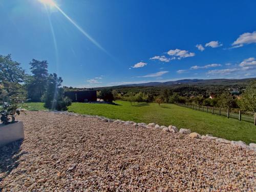 a garden with rocks and a field and a fence at Casa Slarku - Luxury Container Houses in Miskolc
