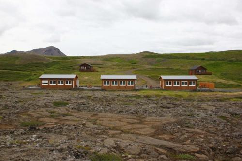 two houses in a field with mountains in the background at Hlid Bed and Breakfast in Myvatn