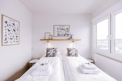 two beds in a room with white walls and windows at Hlid Bed and Breakfast in Myvatn