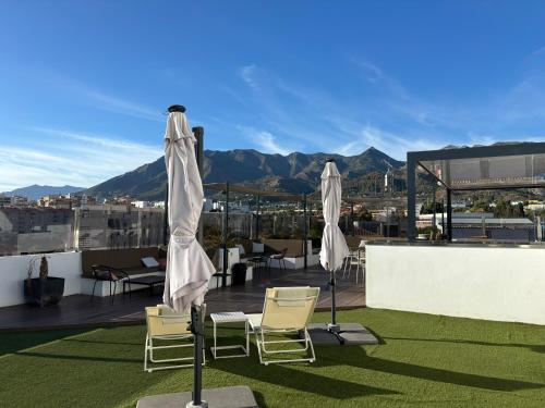 a patio with chairs and umbrellas on a roof at DAOS Suites & Terrace Marbella in Marbella