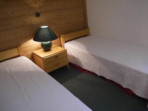 une chambre avec deux lits et une lampe sur une table de chevet dans l'établissement Appartement à Méribel, au pied des pistes, avec balcon et casier à skis - FR-1-355-137, à Méribel