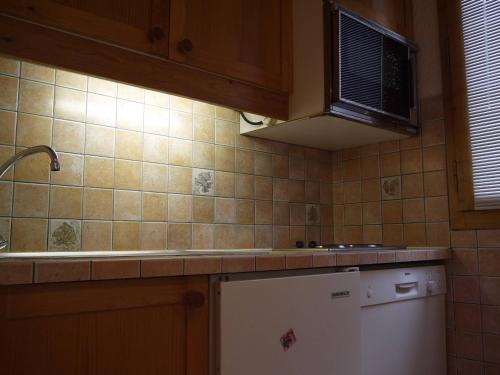 La cuisine est équipée d'un réfrigérateur blanc et d'un four micro-ondes. dans l'établissement Appartement skis aux pieds pour 6 personnes à Méribel - FR-1-355-146, à Méribel