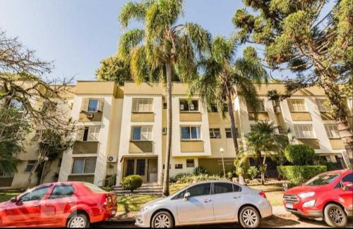 three cars parked in front of a building with palm trees at Apartamento perto da Orla em frente ao Beira Rio in Porto Alegre