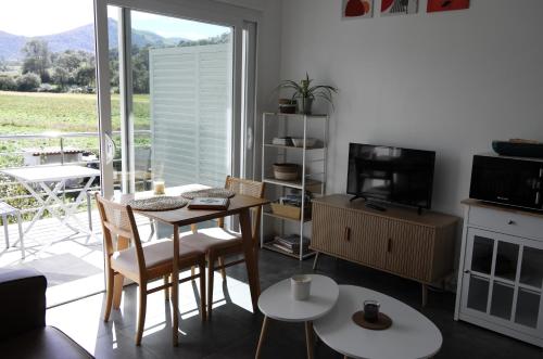 un salon avec une table, des chaises et une télévision dans l'établissement Gîtes Jara et Mendia, Maison Eguzki-Lore, Saint-Jean-Pied-de-Port, Pays Basque, à Saint-Jean-Pied-de-Port