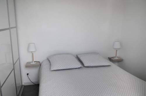 a white bed with two pillows and two lamps at Gîtes Jara et Mendia, Maison Eguzki-Lore, Saint-Jean-Pied-de-Port, Pays Basque in Saint-Jean-Pied-de-Port