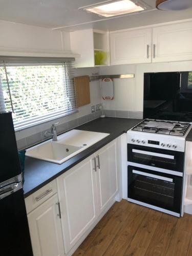 a kitchen with white cabinets and a stove and a sink at Jos lakes Escape in Cockermouth
