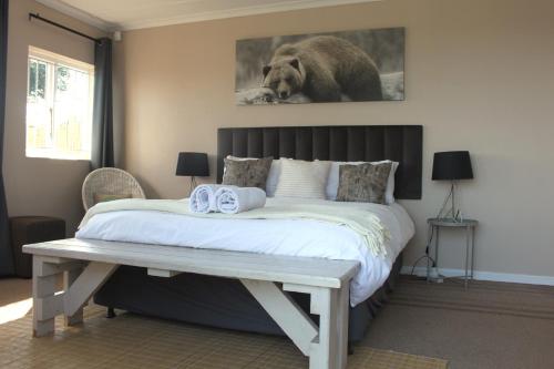 a bedroom with a large bed with a bench next to it at Fever Tree Cottage in Winston Park