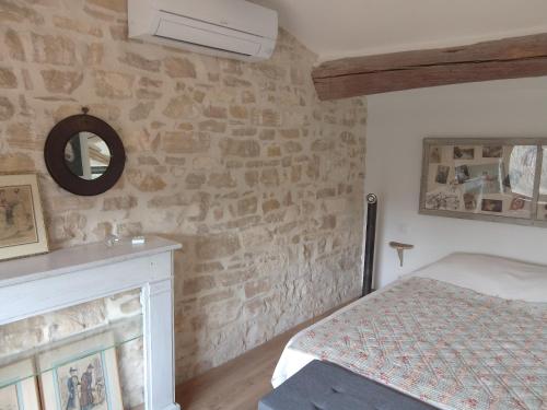 - une chambre dotée d'un mur en pierre avec un lit et un miroir dans l'établissement Le Souliadou, à Saint-Didier