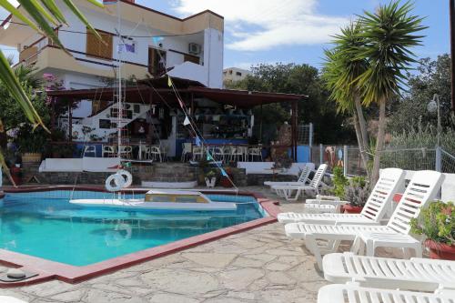 a pool with white chairs next to a building at Milos Apartments in Elounda