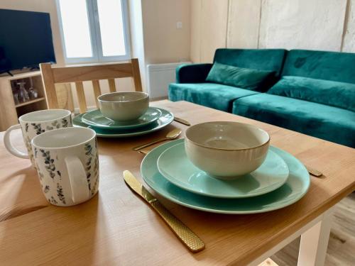 une table en bois avec deux tasses et des assiettes dans l'établissement Green Book - T2 avec parking, à Vierzon