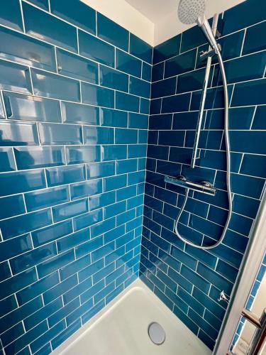 bagno con piastrelle blu, doccia e vasca di Blue Vervet - T2 avec parking a Vierzon