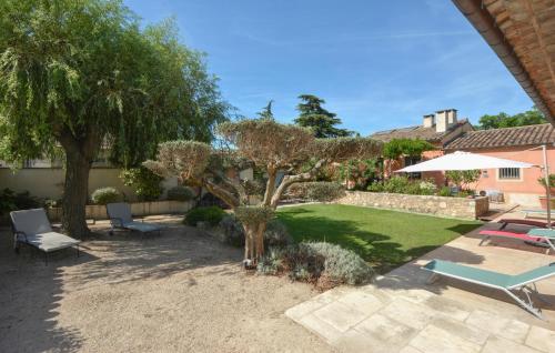 a garden with a tree and chairs and an umbrella at Stunning Home In Noves With Wifi in Noves