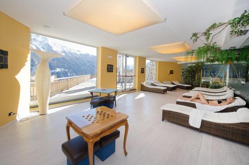 a living room with a person laying on a bed at Family & Wellness Hotel Fontana in Vigo di Fassa