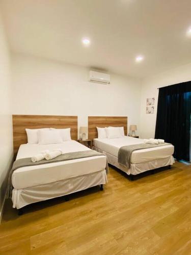 two beds sitting in a room with wooden floors at Casa Jocabeth in Flores
