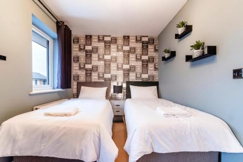 two beds in a room with white sheets at Black Brick Stays, Great Location, Free Parking, Fast Wi-Fi, Families & Contractors Welcome in Peterborough