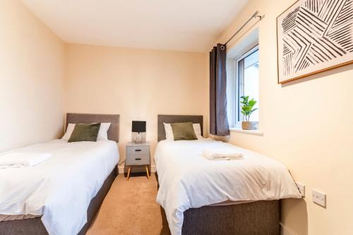 two beds in a room with a window at Stylish Modern Stay Prime Location Free Parking & Fast Wi-Fi in Peterborough