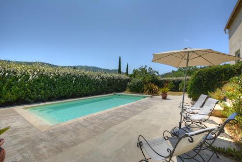 a swimming pool with an umbrella and two chairs and a table at Villa Néoulaise 12 couchages in Néoules