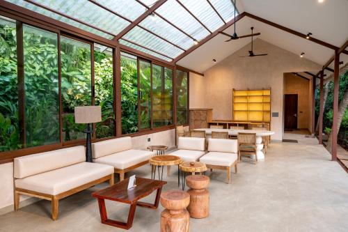a conservatory with white furniture and large windows at Palma Beach Resort in Mandrem
