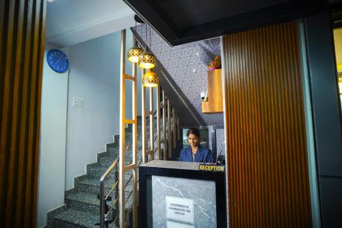 a man standing next to a staircase with a tv at Hotel Rama in Gorakhpur