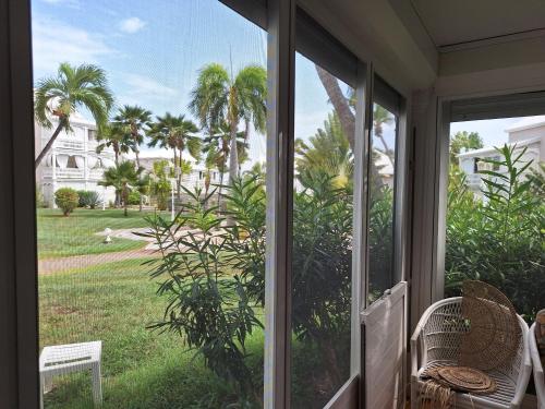 a screened porch with a view of a yard with palm trees at Dolce Vita Anse Margot in Marigot