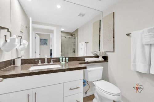a white bathroom with a toilet and a sink at Bahia Mar Solare Beachfront Resort Condos with Two Pools in South Padre Island