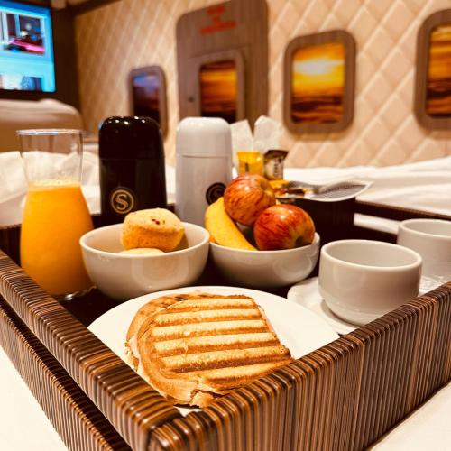 un vassoio per la colazione con pane tostato, frutta e succo d'arancia di Sensitive a Santo Antônio