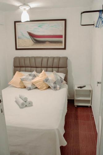 a bedroom with a white bed with a painting on the wall at Casa da Carioca com vista para Floresta Tijuca in Rio de Janeiro