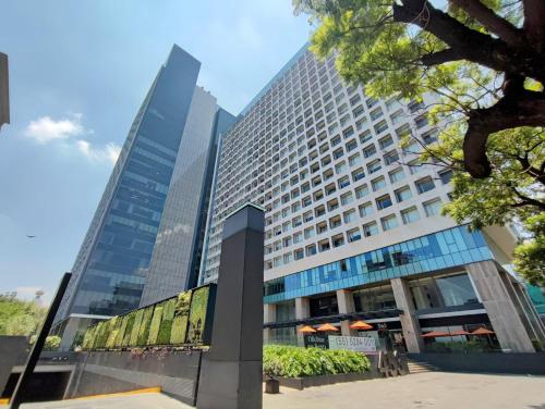 a tall glass building with trees in front of it at Luxurious High-Rise HS WiFi, amazing city views in Mexico City