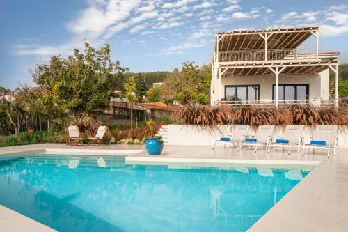 Una piscina con sillas y una casa al fondo. en Villa Aura Boutique Escape with Heated Pool near Albena, en Rogachevo