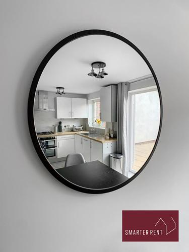 a round mirror hanging on a white wall with a kitchen at Farnham - 2 Bedroom House - With Garden and Parking in Hale