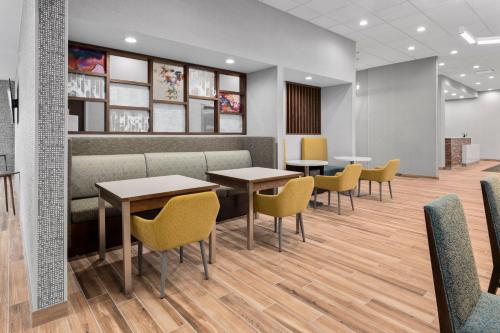 a waiting room with tables and yellow chairs at Hampton Inn Saline in Saline