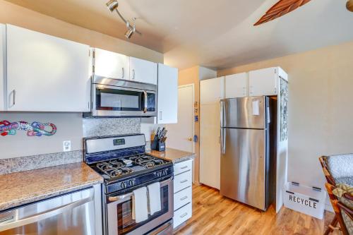 a kitchen with white cabinets and a stainless steel refrigerator at Kaunakakai Condo with Private Lanai and Ocean Views! in Kaunakakai