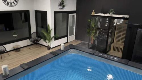 une grande piscine dans un salon avec vue sur un bâtiment dans l'établissement Eau bon'heure, à La Bassée