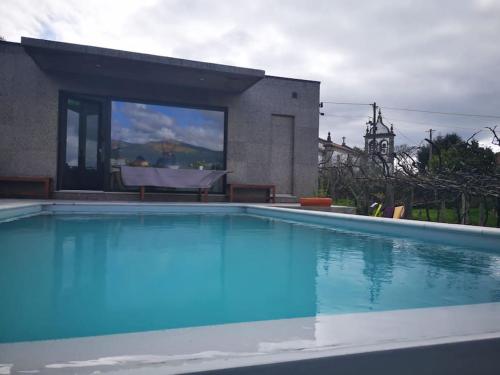 a swimming pool with blue water in front of a house at Casa Da Barroca in Arcos de Valdevez