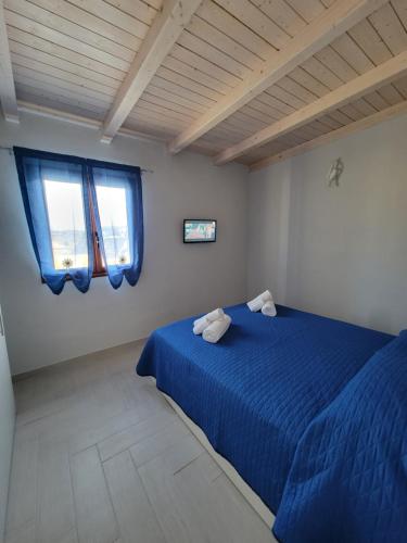 a bedroom with a blue bed and two windows at Appartamenti Vincenzo Lampedusa in Lampedusa