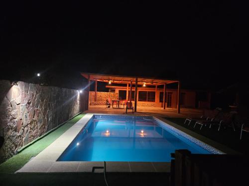 a swimming pool at night with a stone wall at Ckausama North in San Pedro de Atacama