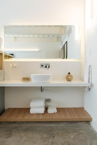 a white bathroom with a sink and towels at Vain Boutique Hotel in Buenos Aires
