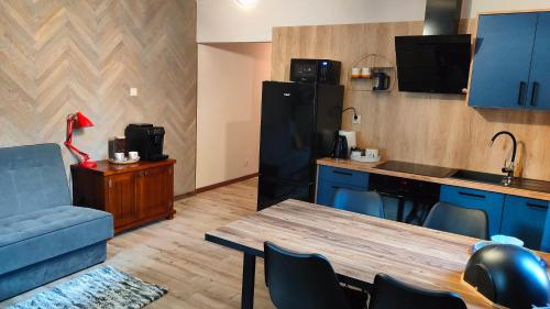 a kitchen with blue cabinets and a table and a blue couch at Apartament Pod Czereśnią in Suwałki