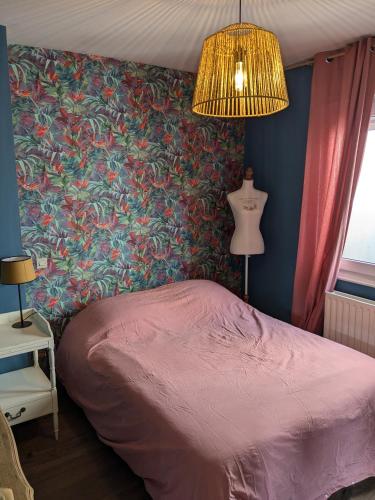 - une chambre avec un lit rose et un papier peint floral dans l'établissement Les jardins de Romy, à Calais